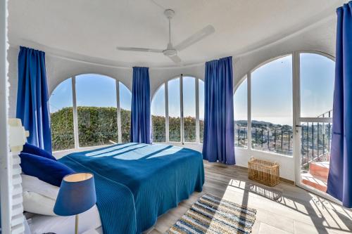 sypialnia z niebieskim łóżkiem i dużymi oknami w obiekcie Villa El Capitan by Vamdays w mieście Benissa