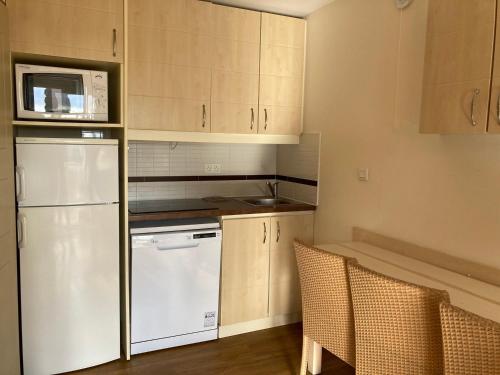 La cuisine est équipée d'un réfrigérateur blanc et d'un four micro-ondes. dans l'établissement Appartement 3 pièces avec terrasse, piscine et parking à Saint-Raphaël - FR-1-504-606, à Saint-Raphaël