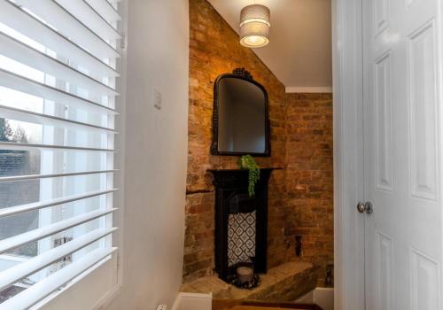 霍舍姆Talbot Lane Cottage Horsham By My Getaways的走廊上的砖墙,设有壁炉