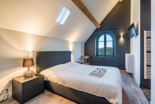 a bedroom with a large bed and a window at d'Oude Schaapskooi, de luxe vakantiehoeve in Damme in Damme