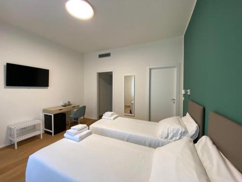 a room with two beds and a desk and a television at FORESTERIA DANSI in Varese