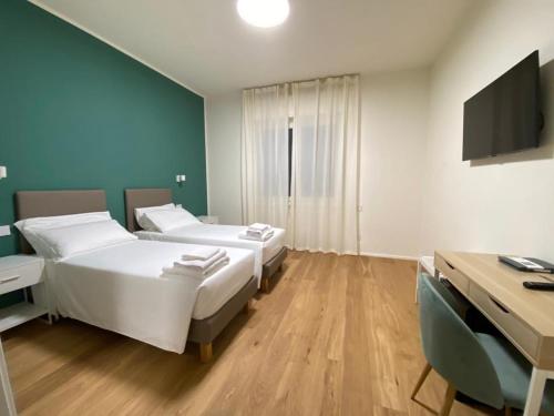 Duas camas num quarto com uma secretária e uma televisão. em FORESTERIA DANSI em Varese