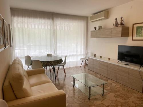 ein Wohnzimmer mit einem Sofa und einem Tisch in der Unterkunft Appartamento Ellidor in Lido di Jesolo
