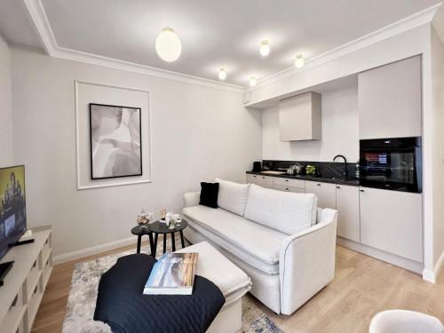 a living room with a white couch and a kitchen at Kurkowa Apartments in Szczecin