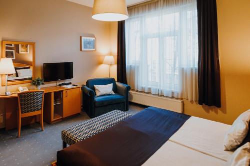 ein Hotelzimmer mit einem Bett, einem Stuhl und einem Schreibtisch in der Unterkunft Hotel Piano in Szeged