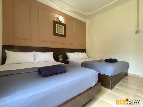 two beds in a hotel room with blue pillows at Afamosa Villa with private pool by BeeStay in Kampong Alor Gajah