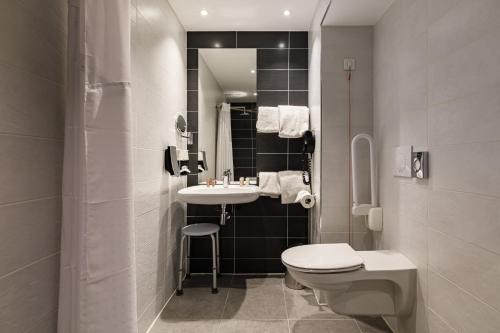 a white bathroom with a sink and a toilet at Holiday Inn Clermont Ferrand Centre, an IHG Hotel in Clermont-Ferrand