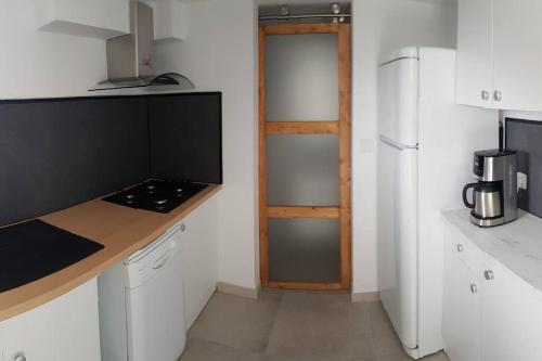 - une cuisine blanche avec un comptoir et un réfrigérateur dans l'établissement Joli appartement 2 chambres à Martigues, à Martigues