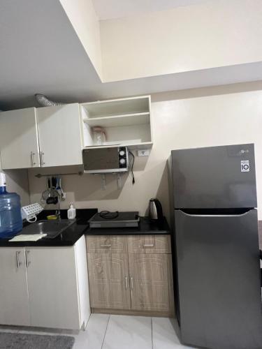 een keuken met een zwarte koelkast en witte kasten bij SunVida Tower in Cebu City