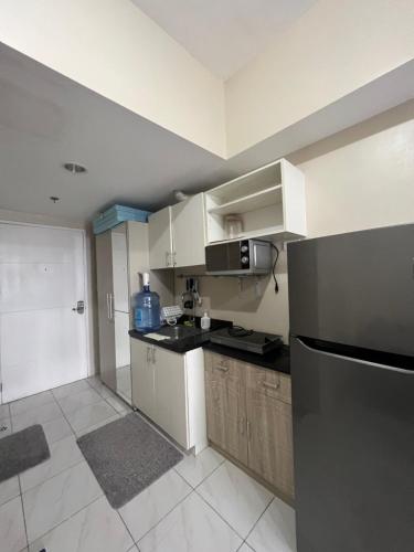 een keuken met een zwarte koelkast en witte kasten bij SunVida Tower in Cebu City