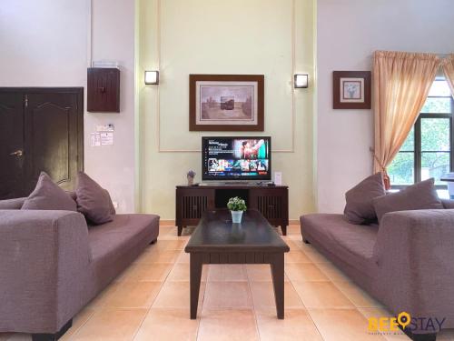 ein Wohnzimmer mit 2 Sofas und einem TV in der Unterkunft Afamosa Villa with private pool by BeeStay in Kampong Alor Gajah