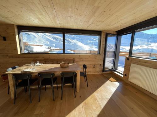 a dining room with a table and chairs and windows at Penthouse au cœur de Val Thorens in Val Thorens