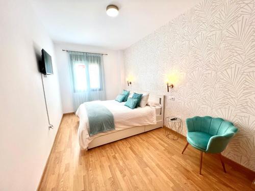 a bedroom with a bed and a blue chair at Apartamento Sorolla Center in Ayamonte