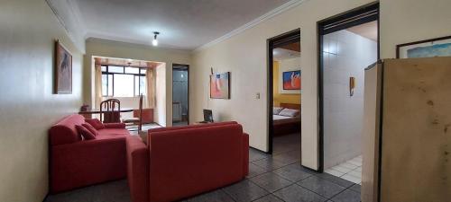 a living room with a red couch and a bedroom at Fortaleza Flat Executivo in Fortaleza