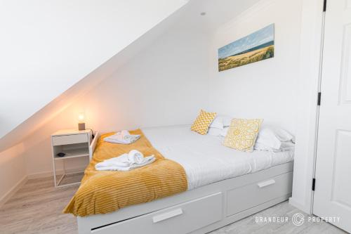 um quarto branco com uma cama com um cobertor amarelo em BMTH town centre 2 min walk, 3 bed house, outside space and parking - Driftwood em Bournemouth