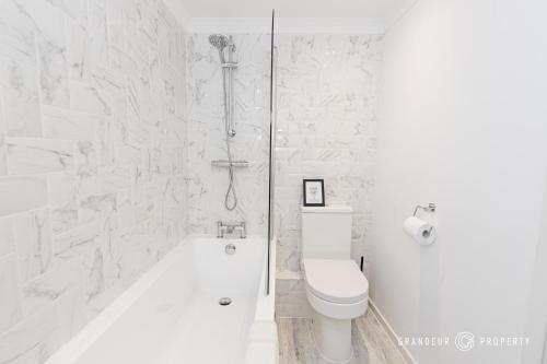 Un baño blanco con inodoro y ducha. en Driftwood by Grandeur Property, en Bournemouth