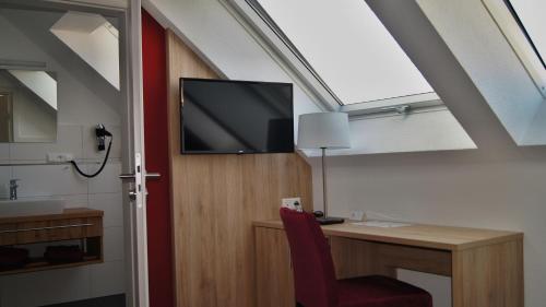 a room with a desk and a tv on the wall at Gästehaus Winzerhof am Schlierbach in Weiler bei Weinsberg