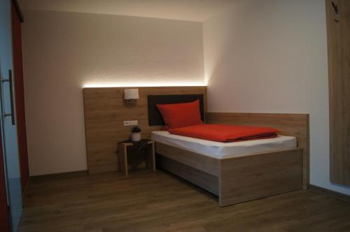 a small bedroom with a bed with a red pillow at Gästehaus Winzerhof am Schlierbach in Weiler bei Weinsberg