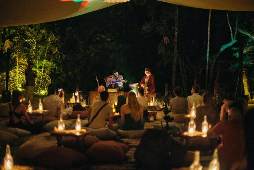 un grupo de personas sentadas alrededor de una actuación por la noche en Our Habitas Tulum, en Tulum