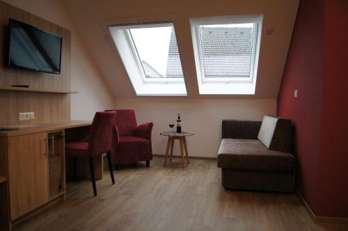 a living room with a tv and a couch and chairs at Gästehaus Winzerhof am Schlierbach in Weiler bei Weinsberg