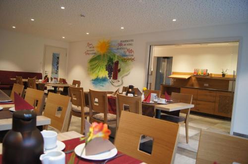 a restaurant with tables and chairs and a piano at Gästehaus Winzerhof am Schlierbach in Weiler bei Weinsberg
