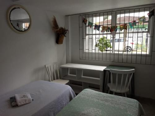 een slaapkamer met 2 bedden, een tafel en een raam bij ANNANDA in Florianópolis