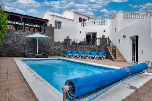 a pool with blue chairs and a house at Casa El Paraiso - Private Pool, Jacuzzi, Air-con and BBQ By Lanzarote Vacation Homes in Tías