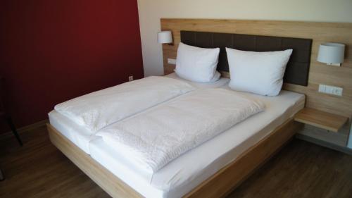 a large bed with white sheets and pillows at Gästehaus Winzerhof am Schlierbach in Weiler bei Weinsberg
