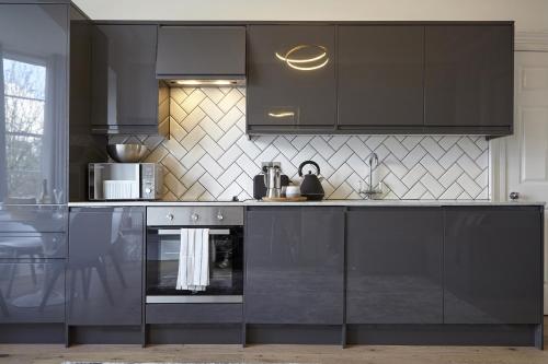 a kitchen with black cabinets and a stove at nap Bristol Clifton in Bristol