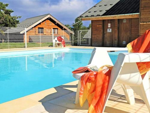 une piscine avec deux chaises et une maison dans l'établissement Studio au rez-de-chaussée avec parking, animaux admis - FR-1-504-581, à Saint-Étienne-en-Dévoluy