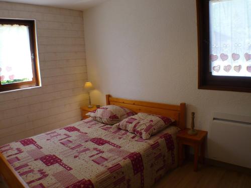une chambre avec un lit avec une couette dessus dans l'établissement T2 au calme, proche centre village - Terrasse et parking - FR-1-629-16, à Samoëns