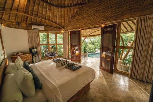 a bedroom with a large bed in a room with windows at Kayuma Villas Lombok in Selong Belanak