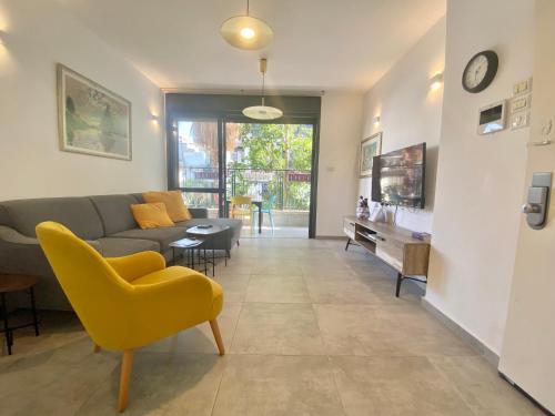 a living room with a couch and a yellow chair at Lapin 9 - By Beach Apartments TLV in Tel Aviv