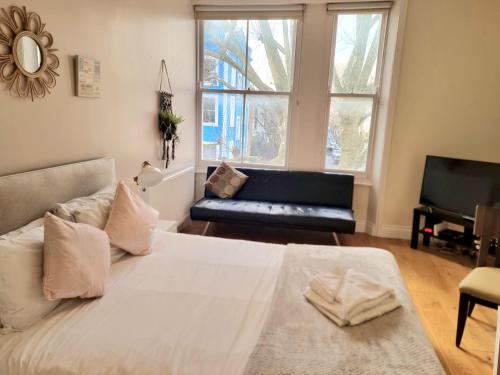 ein Schlafzimmer mit einem großen weißen Bett und einem Sofa in der Unterkunft Oxford Gardens Apartments in London