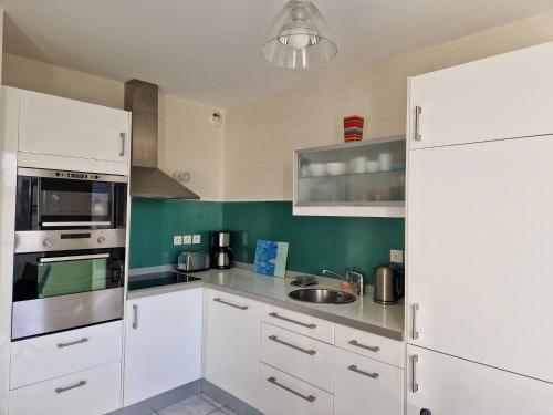 - une cuisine avec des appareils électroménagers blancs et des murs verts dans l'établissement Apartment in Brittany near Sandy Beach, à Pléneuf-Val-André