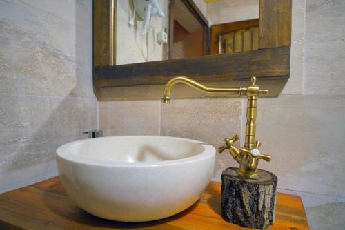 lavabo blanco en una encimera de madera en el baño en Babili Cappadocia Cave Hotel, en Nevşehir