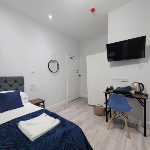 a bedroom with a bed and a desk and a television at Argyle Square Hotel in London