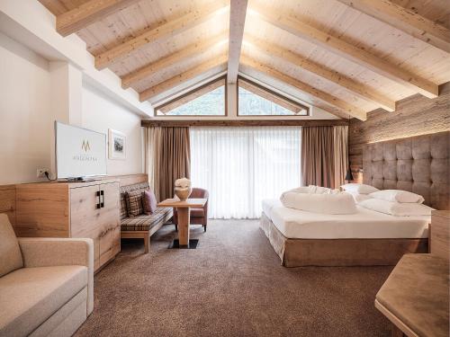 a hotel room with two beds and a couch and a tv at Hotel Magdalena Mayrhofen in Mayrhofen
