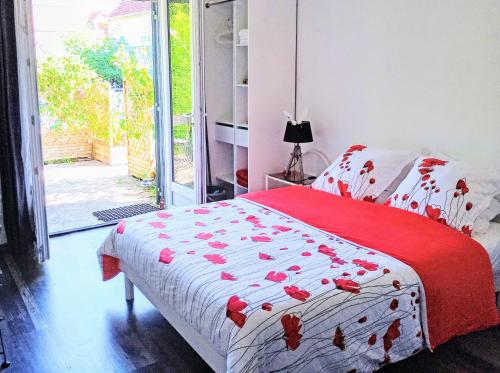 a bedroom with a bed with a red and white blanket at Studio Les coquelicots in Saint-Romain-sur-Cher