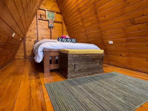 ein Schlafzimmer mit einem Bett in einer Holzhütte in der Unterkunft Glamping El Reencuentro in Machachi