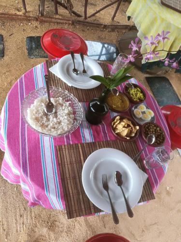 a table with plates and utensils on a pink blanket at Rosa Shashi Cabanas in Galle