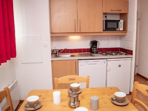 une petite cuisine avec une table en bois et une salle à manger dans l'établissement Studio PMR 2 Pers avec Balcon Sud-Est et Accès Piscine, à 300m des Pistes - FR-1-504-341, à Puy-Saint-Vincent