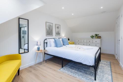 sypialnia z dużym łóżkiem i żółtym krzesłem w obiekcie The Pinkish House - 4 bed home in the town centre w mieście Blairgowrie