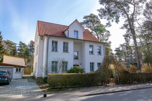 ein weißes Haus mit rotem Dach in der Unterkunft Ferienwohnung Seestraße in Lubmin