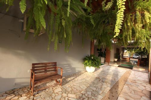 a wooden bench sitting next to a building with plants at IPÊ PARK Convention Hotel in Sao Jose do Rio Preto