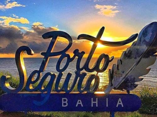 una señal para una playa con la puesta de sol en el fondo en casa da paz, en Porto Seguro