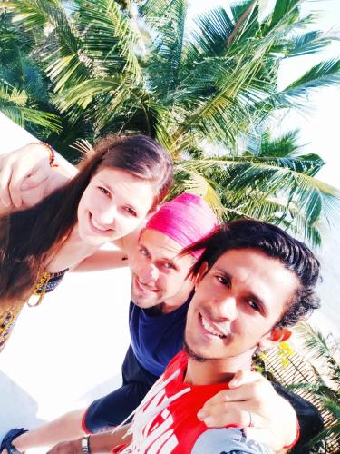 three people posing for a picture in front of a palm tree at Rosa Shashi Cabanas in Galle