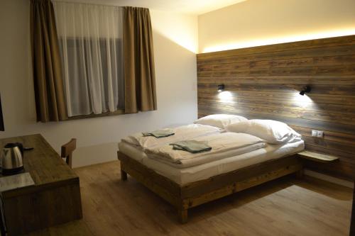 a bedroom with a bed and a wooden headboard at Tri kopy*** - penzión, reštaurácia a pizza in Smrečany
