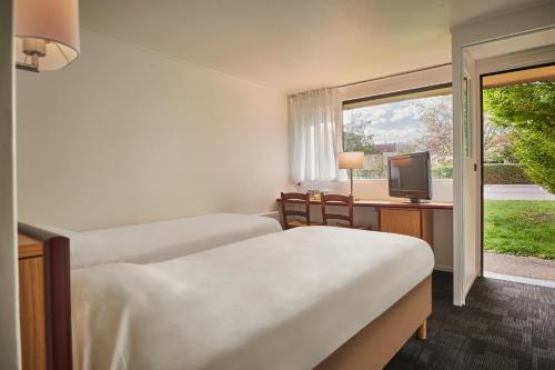 a room with two beds and a television and a window at Kyriad Direct Epinal in &Eacute;pinal