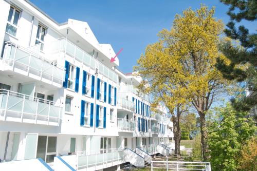 - un bâtiment blanc avec des fenêtres et des arbres bleus dans l'établissement FeWo im maritimen Flair - 100m zu Strand & Seebrücke, à Zingst